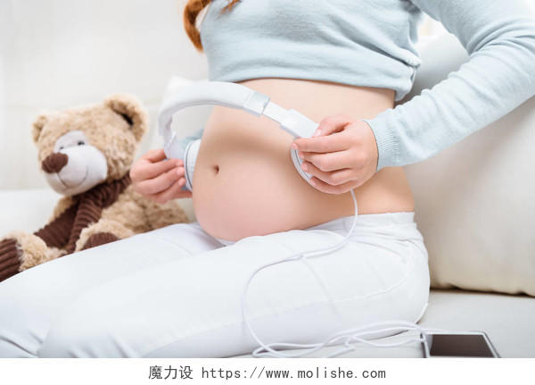 孕妇在她的肚子上戴耳机